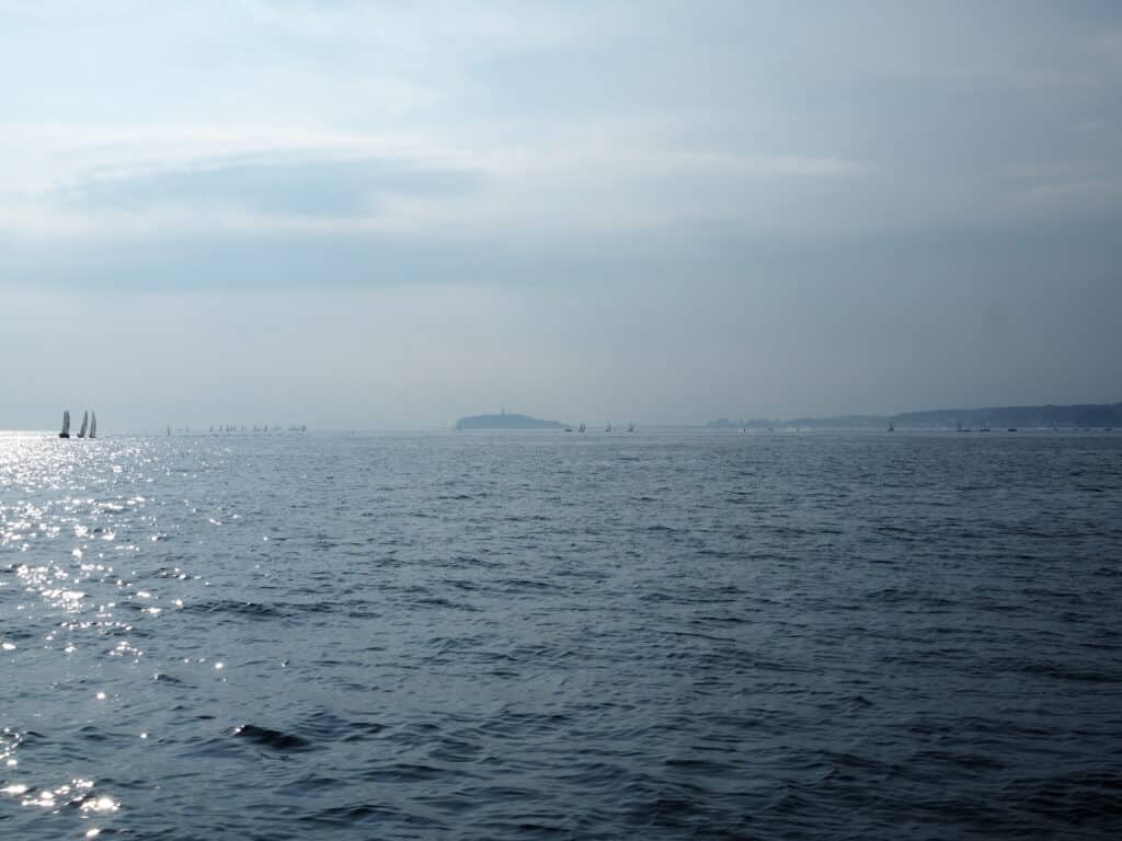 陽の光がきらめく相模湾の海と遠くの帆船
